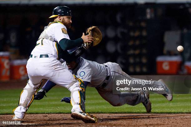 Jean Segura of the Seattle Mariners dives into home plate to score the game winning run ahead of a tag from Jonathan Lucroy of the Oakland Athletics...
