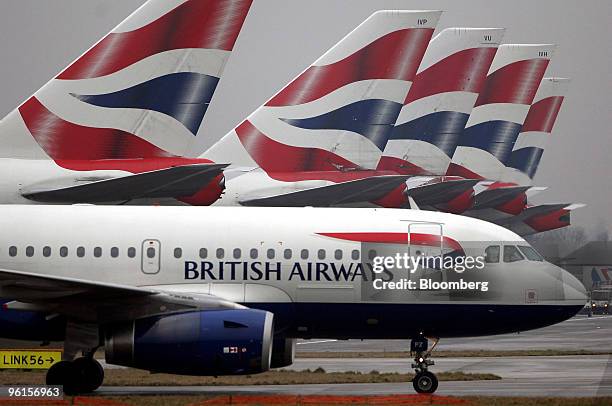 British Airways airplane taxis towards the runway, passing jets sitting at Terminal 5 at Heathrow airport in London, U.K., on Monday, Jan. 25, 2010....