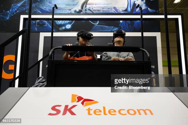 Visitors wear virtual reality headsets while playing a video game at the SK Telecom Co. Booth during the World IT Show 2018 in Seoul, South Korea, on...