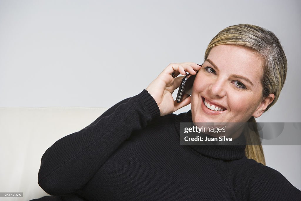 Blonde woman sitting on sofa using mobile phone