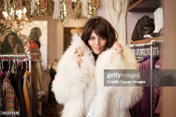 portrait of young woman wearing fur coat at boutique - woman in fur coat stock-fotos und bilder