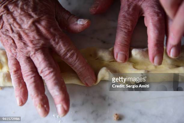 pressing fresh pasta sheet around pieces of stuffing to make tortellini - lodi lombardy stock pictures, royalty-free photos & images