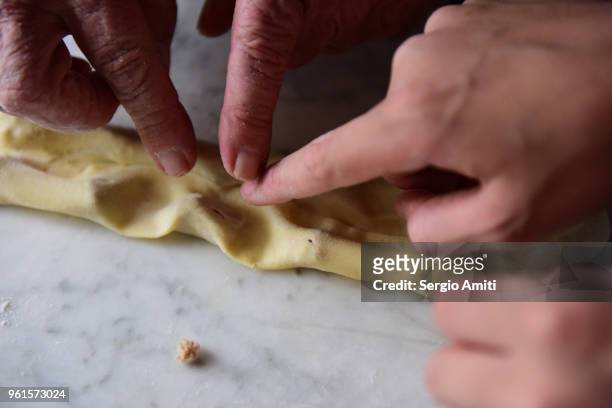 pressing fresh pasta sheet around pieces of stuffing to make tortellini - lodi lombardy stock pictures, royalty-free photos & images