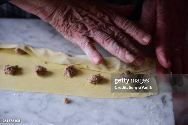 pressing fresh pasta sheet around pieces of stuffing to make tortellini - lodi lombardy stock pictures, royalty-free photos & images