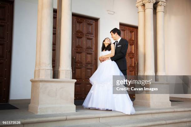 newlywed couple standing outside church - married church stock pictures, royalty-free photos & images