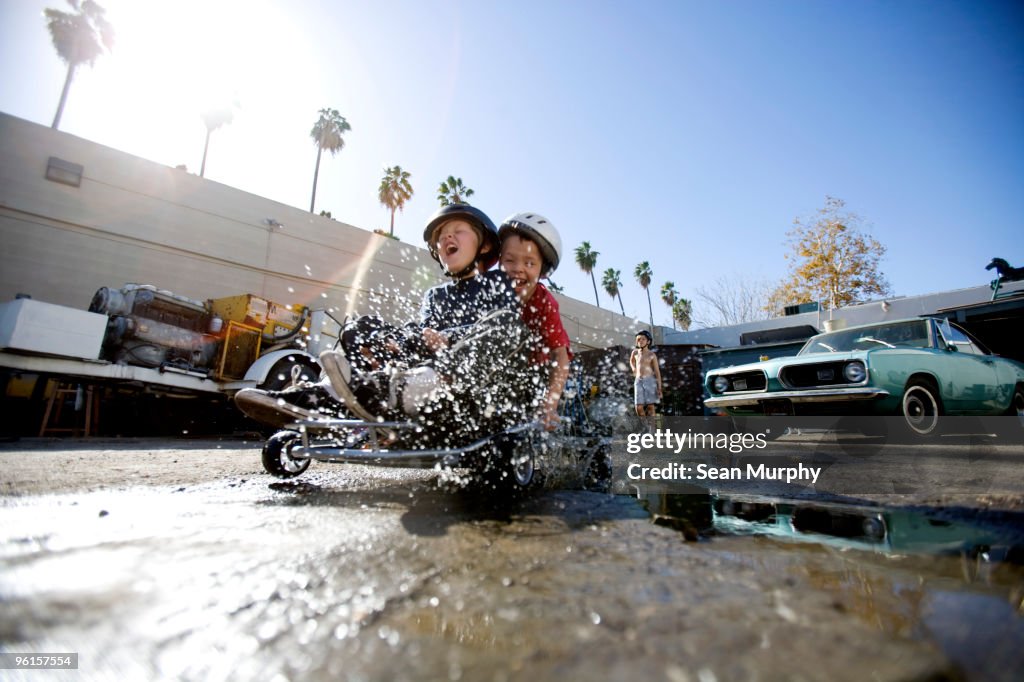 Boys splashing through mudpuddle