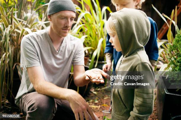 man showing earthworm to children in garden - earthworm stock pictures, royalty-free photos & images