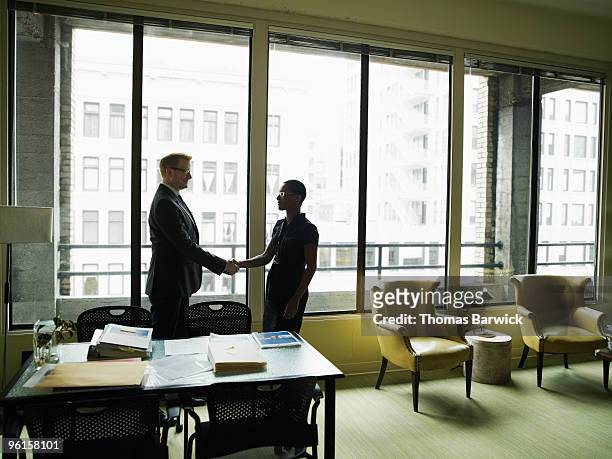 two businesspeople shaking hands in office - leanintogether stock pictures, royalty-free photos & images