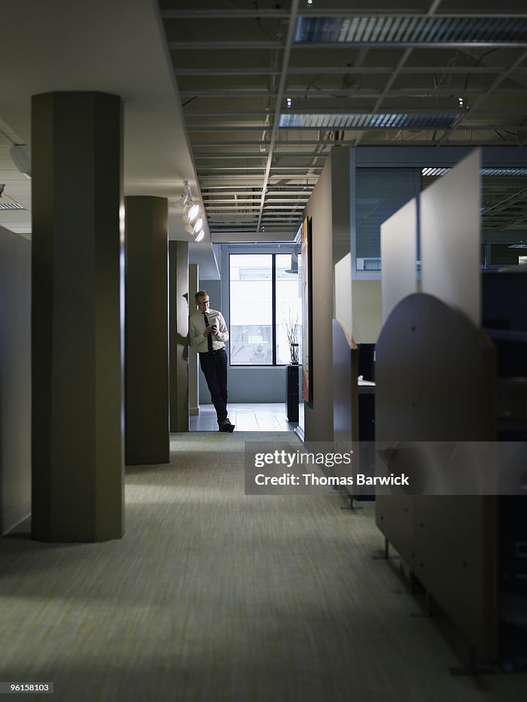 Businessman leaning on post in office hallway