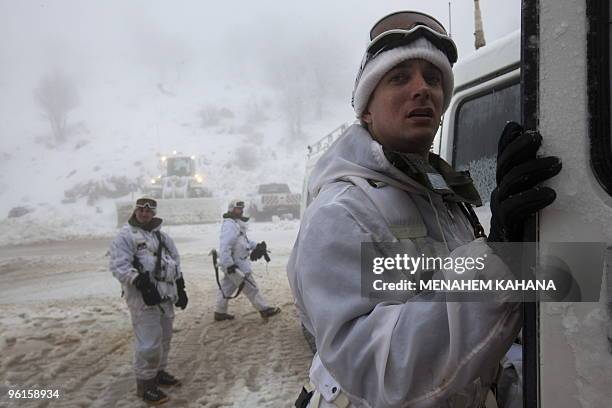 Israeli soldiers walk next to a snow-mobile at a military base on the snow-covered slopes of Mount Hermon on January 25, 2010 in the Golan Heights,...