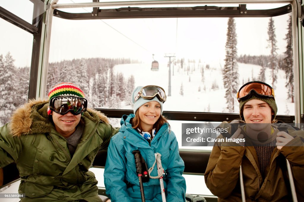 Portrait of happy skiers sitting in overhead cable car