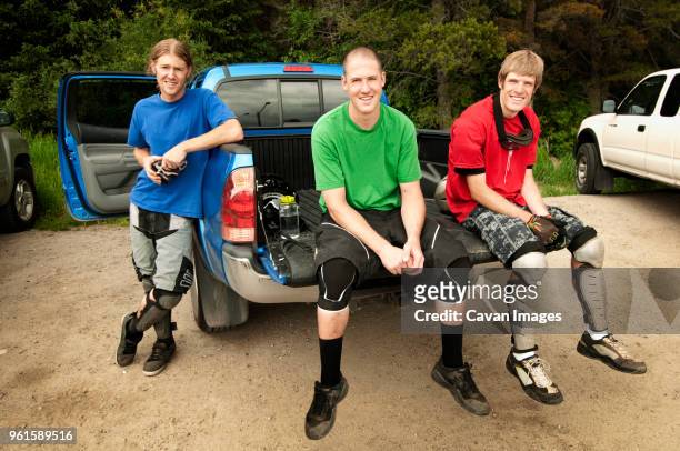 portrait of cyclists sitting on pick-up truck in forest - shin guard stock-fotos und bilder