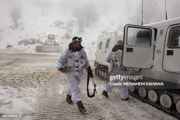 Israeli soldiers walk next to a snow-mobile at a military base on the snow-covered slopes of Mount Hermon on January 25, 2010 in the Golan Heights,...