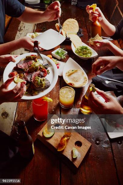 cropped image of people having meal at table - mexican food plate stock pictures, royalty-free photos & images