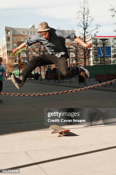 man jumping over chain fence on sunny day - mann freudensprung sonne vorderansicht leger stock-fotos und bilder