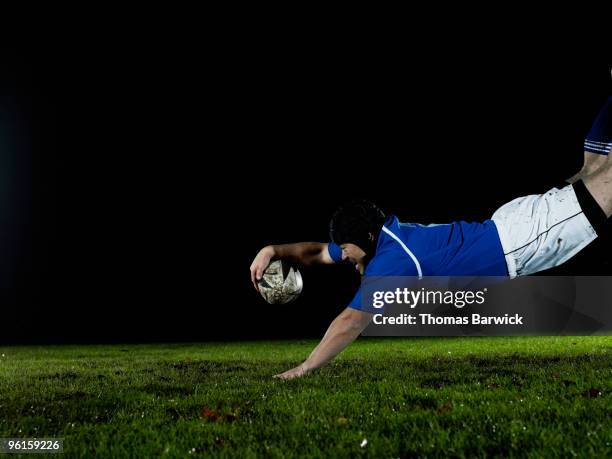 male rugby player diving for try on field at night - rugby - fotografias e filmes do acervo