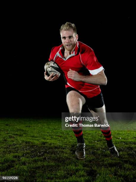 male rugby player running with ball on field - rugby ball stock-fotos und bilder