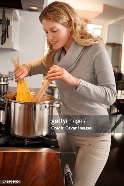 woman cooking spaghetti in kitchen - holding saucepan stock pictures, royalty-free photos & images