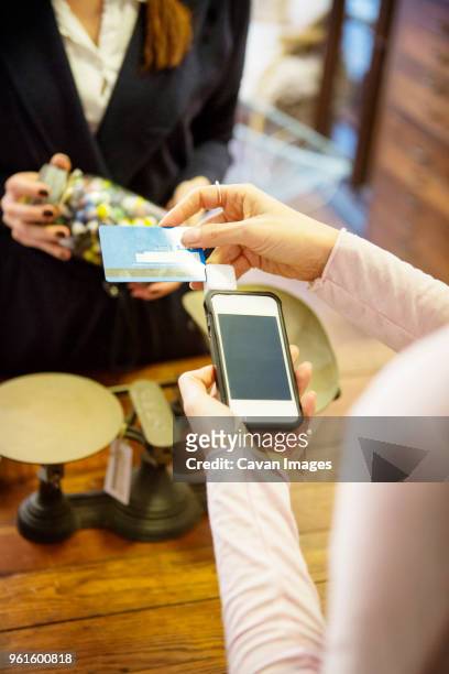 high angle view of woman swiping credit card in credit card reader - swipe right stock pictures, royalty-free photos & images