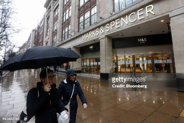 Pedestrian carries an umbrella to shelter from the rain as she walks past a Marks & Spencer Plc store on Oxford Street in London, U.K., on Thursday,...
