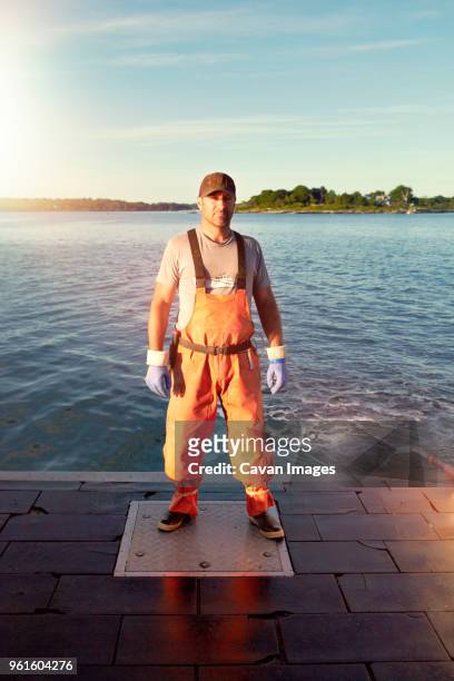 portrait of confident fisherman standing on pier - pêcheur photos et images de collection