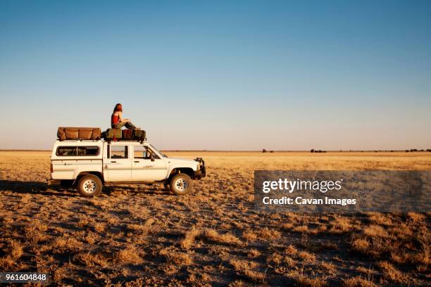 side view of woman sitting on off-road vehicle at field - car camping luggage stock pictures, royalty-free photos & images