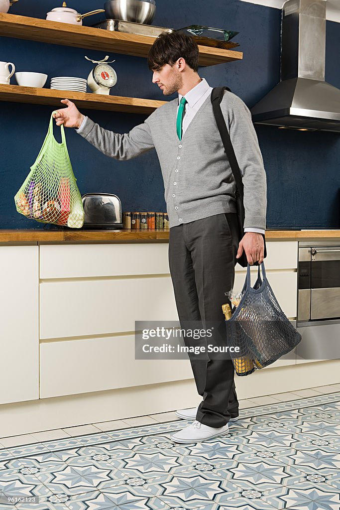 Young man in kitchen with groceries