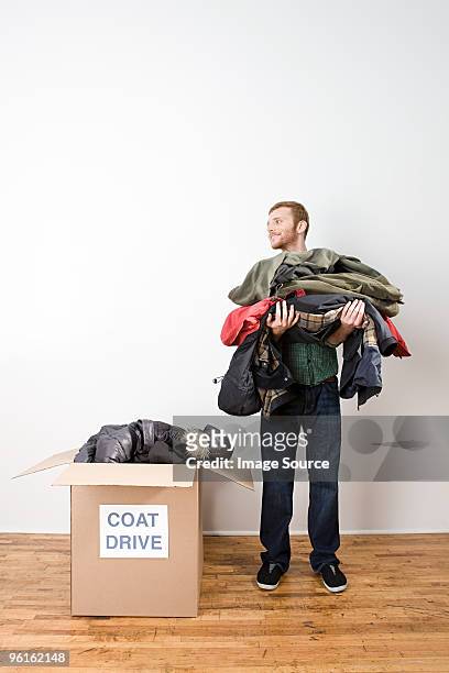 man with coats for coat drive - clothing donation stock pictures, royalty-free photos & images