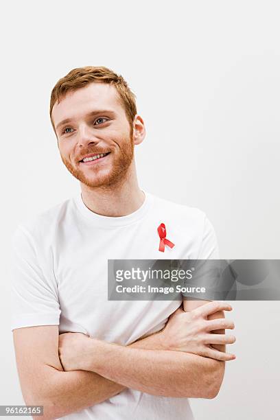 hombre usa cinta roja contra el sida - aids ribbon fotografías e imágenes de stock