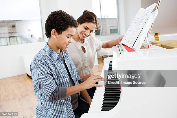 mujer dando piano lección a boy - kids instruments fotografías e imágenes de stock