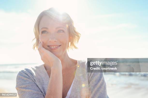 schöne reife frau porträt am strand. - happy face stock-fotos und bilder