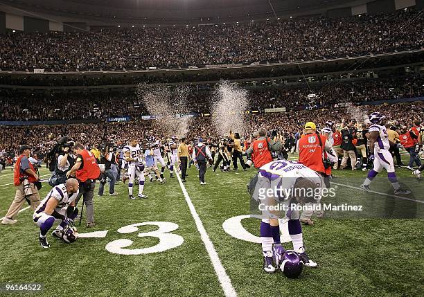 Ben Leber and Brian Robison of the Minnesota Vikings remain on the field dejected as the New Orleans Saints celebrate their 31-28 overtime win during...