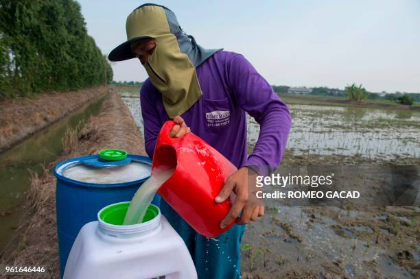 This picture taken on March 13, 2018 shows a Thai farmer preparing a vat of pesticide spray at farm in Suphan Buri province. - Thailand was ranked...