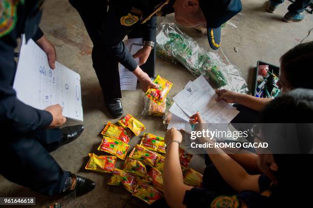 This picture taken on March 13, 2018 shows police and Ministry of Agriculture personnel raiding a warehouse looking for pesticides products in Suphan...