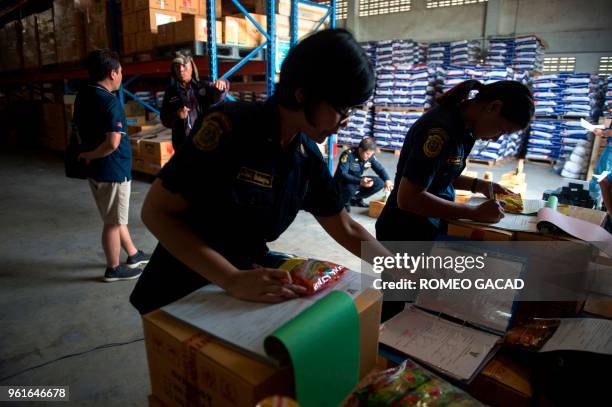 This picture taken on March 13, 2018 shows police and Ministry of Agriculture personnel inspecting alleged fake pesticides seized during a raid in a...