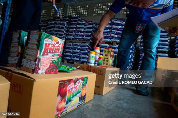 This picture taken on March 13, 2018 shows police and Ministry of Agriculture personnel inspecting alleged fake pesticides seized during a raid in a...