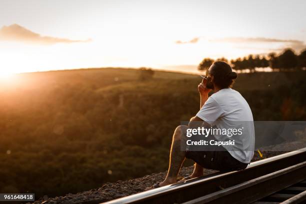 man smoking cigarette sitting on the edge of cliff - train tracks end stock pictures, royalty-free photos & images