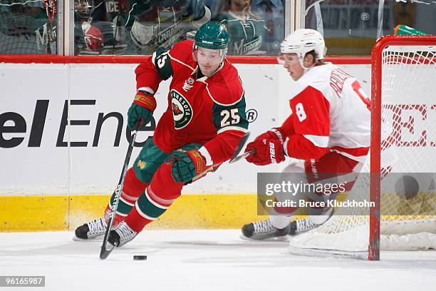 Eric Belanger of the Minnesota Wild handles the puck with Justin Abdelkader of the Detroit Red Wings defending during the game at the Xcel Energy...