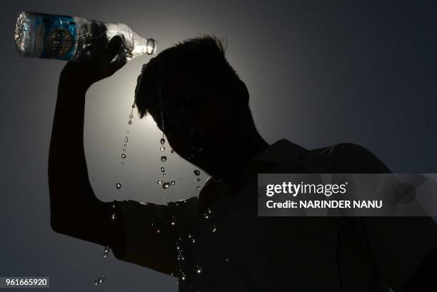 An Indian boy pours water over his head on a hot summer day in Amritsar on May 23, 2018.