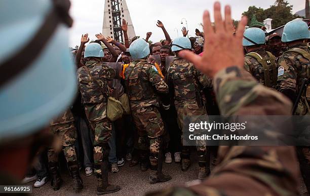 United Nations peacekeepers from Uruguay attempt to hold back a massive crowd during a rice distribution for earthquake-displaced Haitians in front...