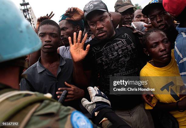 United Nations peacekeepers from Uruguay attempt to hold back a massive crowd during a rice distribution for earthquake-displaced Haitians in front...