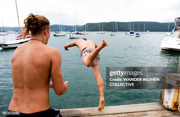 two young males jumping off wharf diving into water - pittwater stock pictures, royalty-free photos & images