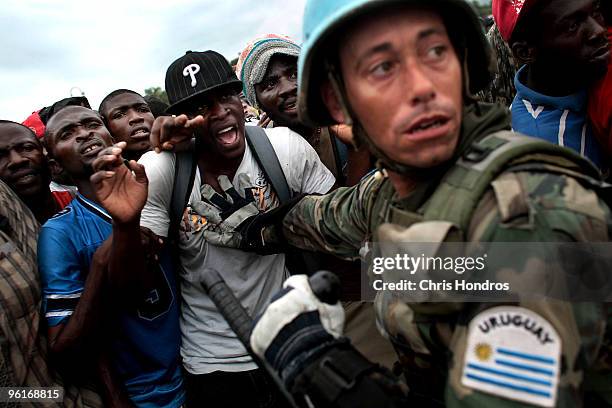 United Nations peacekeeper from Uruguay attempts to control a massive crowd of Haitians jockeying for food in front of the National Palace January...