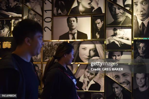 Movie-goers walk past a wall of photos of movie stars at the entrance to a theater in Beijing on May 23, 2018. - China surpassed North America to...