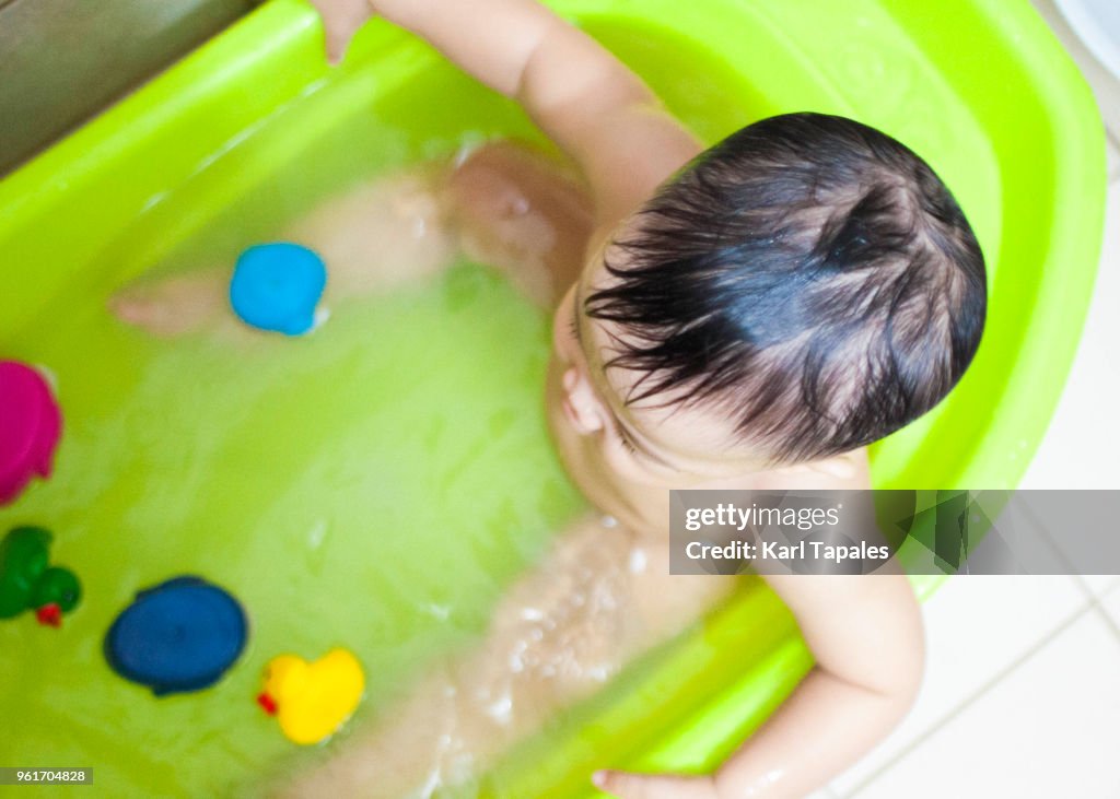 A baby is taking a bath