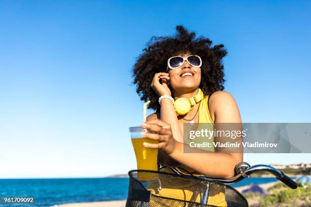 vrouw in gele outfit drinken gele cocktail op het strand - african girl drinking water stockfoto's en -beelden