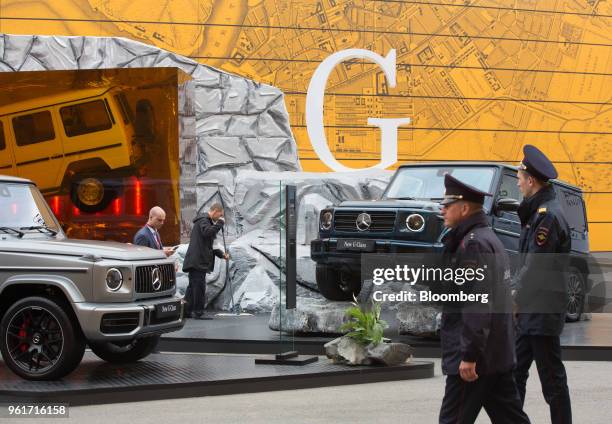 Russian police pass a display of G-Class automobiles on the Mercedes-Benz AG stand at the St Petersburg International Economic Forum in Saint...