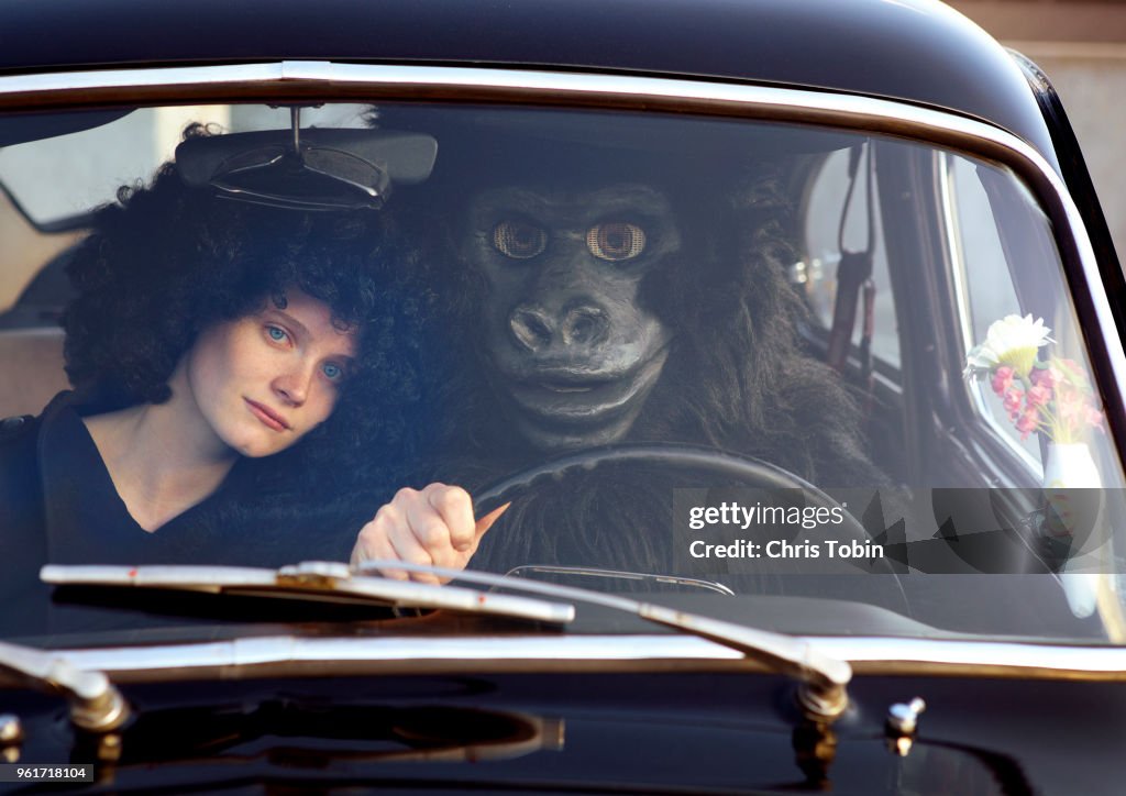 Young woman sitting in car with a gorilla