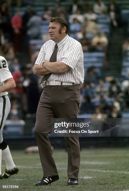 John Madden head coach of the Oakland Raiders on the field watching his team warm-up prior to a mid circa 1970s NFL football game. Madden coached the...