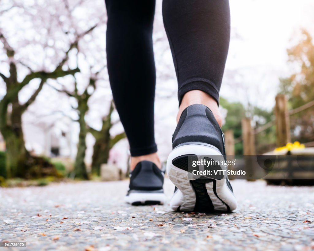 Woman Legs Sport shoe walk in Park outdoor Sakura tree
